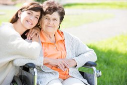 Eine ältere Dame im Rollstuhl wir von einer jungen Frau umarmt | © drubig-photo - Fotolia
